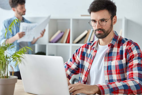 Man blokjeshemd achter laptop